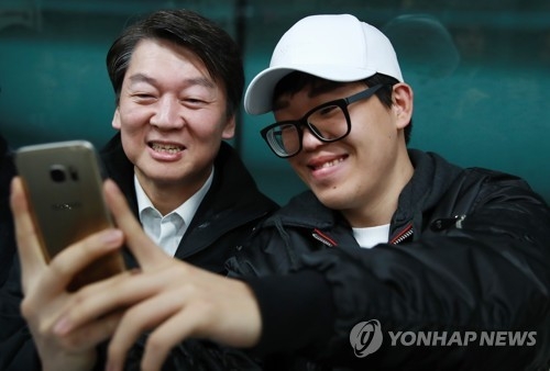 Ahn Cheol-soo (L), the presidential nominee of the centrist People's Party, takes a selfie with a passenger on the subway in Seoul on April 5, 2017. (Yonhap)