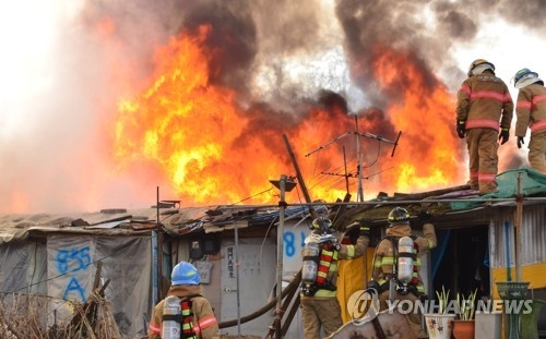 Firefighters try to extinguish the blaze in Guryong Village on March 29, 2017. (Yonhap)