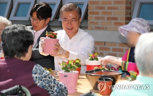 President Moon Jae-in holds up a pot of flowers that he made with senior citizens at a state-operated nursing home in Seoul on June 2, 2017. Moon had pledged during his presidential campaign that he will have the state take care of senile dementia patients. The government is expected to report a plan by the end of the month. (Yonhap)