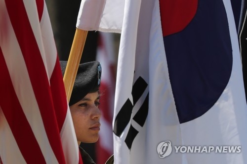 An American soldier serving in South Korea stands between the national flags of South Korea and the U.S. in this file photo. (Yonhap)