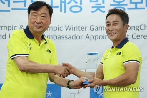 Lee Hee-beom (L), chief of the PyeongChang Organizing Committee for the 2018 Olympic & Paralympic Winter Games (POCOG), shakes hands with South Korean comedian Kim Byoung-man after the latter was appointed honorary ambassador for the PyeongChang Games on July 5, 2017. (Yonhap)
