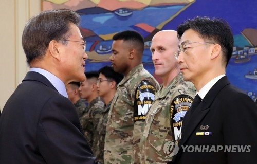 President Moon Jae-in (L) shakes hands with a surgeon who operated on the North Korean solider that suffered multiple gunshot wounds while defecting to South Korea through the joint security area of Panmunjom in November 2017. The president met the surgeon before the start of a special meeting held at his office Cheong Wa Dae on Dec. 1, 2017. The meeting also involved several South Korean and U.S. troops stationed at Panmunjom. (Yonhap)