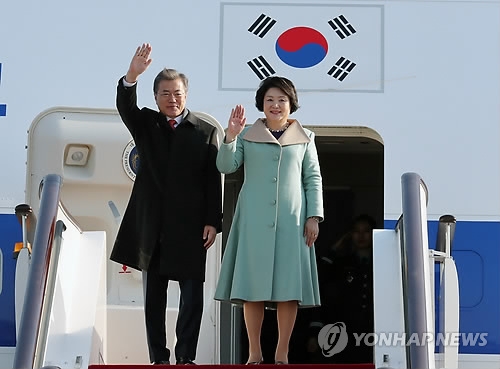 South Korean President Moon Jae-in and his wife Kim Jung-sook wave their hands after arriving in Beijing on Dec. 13, 2017, for a four-day state visit. (Yonhap)
