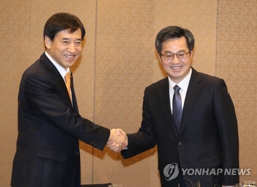 Bank of Korea Gov. Lee Ju-yeol (L) and Finance Minister Kim Dong-yeon shake hands at a breakfast meeting in Seoul on Jan. 4, 2018. (Yonhap)
