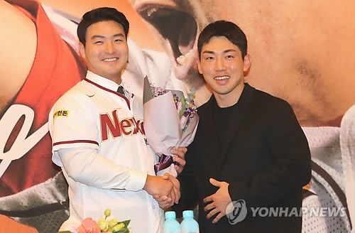 Park Byung-ho of the Nexen Heroes (L) shakes hands with the Heroes' captain, Seo Geon-chang, before Park's press conference in Incheon on Jan. 9, 2018. (Yonhap)