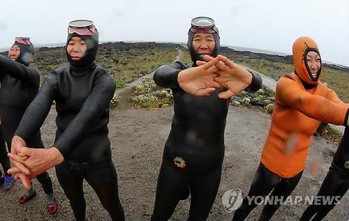 This undated file photo shows a group of haenyeo warming up before diving into waters off Jeju Island. (Yonhap)