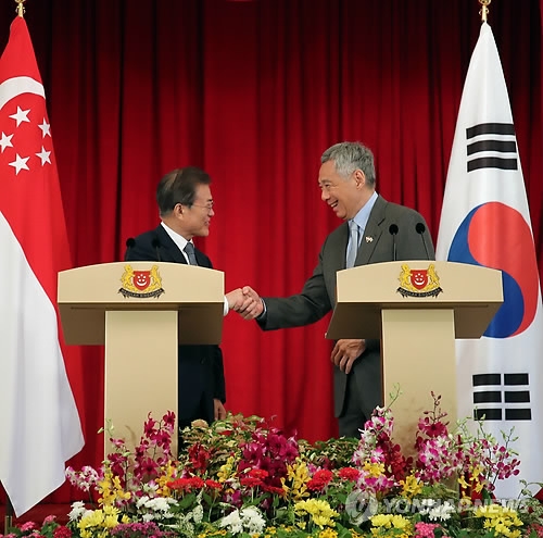 South Korean President Moon Jae-in (L) and Singaporean Prime Minister Lee Hsien Loong shake hands after a joint press conference that followed their bilateral summit in Singapore on July 12, 2018. (Yonhap)