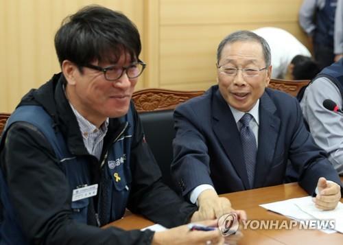 In this file photo, taken Sept. 14, 2018, SsangYong Motor CEO Choi Jong-sik (R) holds the hand of Kim Deuk-joong, chief of the SsangYong Motor branch of the Korean Metal Workers' Union, after signing an agreement to rehire 119 fired workers by 2019. (Yonhap)