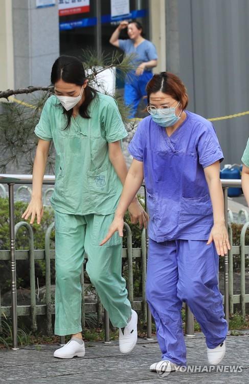 Medical workers walk to a resting place, their bodies soaked with sweat, after working a shift for the service of people infected with the new coronavirus at a hospital in the southeastern city of Daegu on March 19, 2020. (Yonhap)