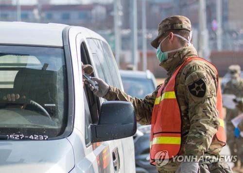 A military guard at U.S. Army Garrison Humphreys in Pyeongtaek, Gyeonggi Province, checks the temperature of a driver to screen entrants to the compound for the novel coronavirus on Feb. 28, 2020, in the photo provided by United States Forces Korea. (PHOTO NOT FOR SALE) (Yonhap)