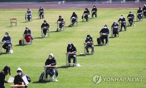 More than 100 job applicants, seated safe distances apart, take a written exam as part of the recruitment process at the city-run Ansan Urban Corp. at a football stadium in Ansan, about 40 km south of Seoul, on April 4, 2020. The urban planning firm decided to hold the test outdoors as a way to prevent the spread of the coronavirus. (Yonhap) 