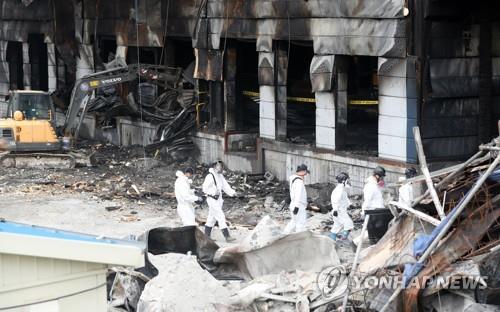 Investigators walk through the site of a warehouse fire in Icheon, Gyeonggi Province, on May 2, 2020. (Yonhap)