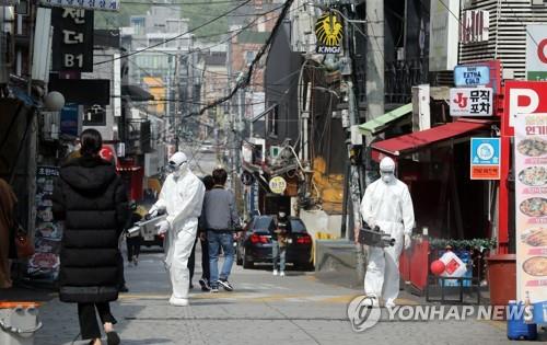 Quarantine officials spray disinfectant on a street in the international district of Itaewon in Seoul, on May 11, 2020, as scores of new cases were reported from people who recently visited entertainment places in the area. (Yonhap)