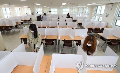 Teachers set up dividers on tables in a cafeteria of Duksoo High School in Seoul on May 13, 2020, to prevent coronavirus infections, ahead of the school's reopening on May 20. (Yonhap)