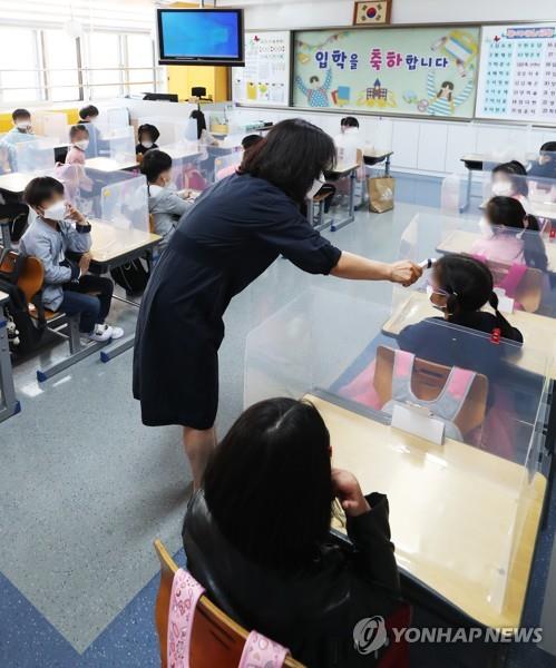 A teacher checks students' temperatures at Hanil Elementary School in the city of Suwon, south of Seoul, on May 27, 2020, amid the coronavirus pandemic. (Yonhap)