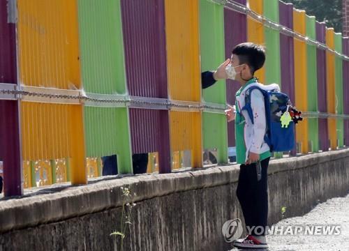 A pupil is encouraged by his mother through a fence as he arrives at Ochi Elementary School in the southwestern city of Gwangju on May 29, 2020, amid the coronavirus pandemic. (Yonhap)