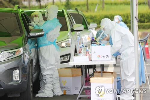 Medical workers conduct drive-through tests for the new coronavirus at a parking lot of a culture and sports center in Hwasun, South Jeolla Province, southwestern South Korea, on Aug. 24, 2020, where students and teachers of an elementary school are to receive such tests after a teacher tested positive for the virus. (Yonhap)