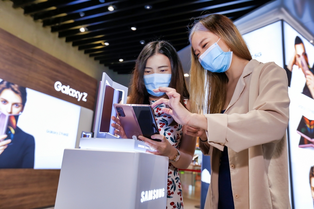 This photo provided by Samsung Electronics Co. on Sept. 18, 2020, shows consumers looking at the Galaxy Z Fold 2 foldable smartphone at Samsung Experience Store in ViVo City shopping mall in Singapore. (PHOTO NOT FOR SALE) (Yonhap)