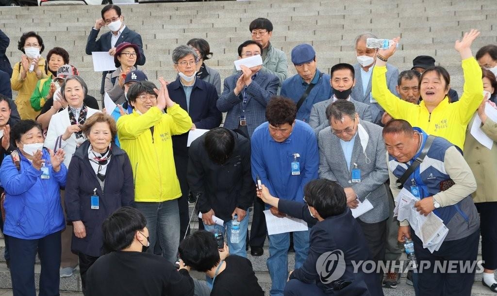 Victims of past state violence and civic activists cheer in front of the National Assembly in Seoul on May 20, 2020, following the passage of a bill on investigating related incidents. (Yonhap)