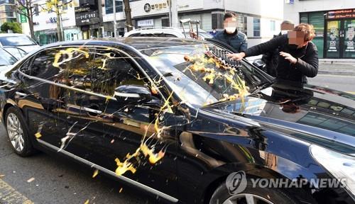 Angry activists throw eggs at a sedan of former President Chun Doo-hwan on Nov. 30, 2020, as he left the Gwangju District Court without apologizing after receiving a suspended eight-month prison sentence for defaming, in his memoir, the late priest Cho Pius, who had testified to witnessing the military shooting at citizens from helicopters during the 1980 Gwangju Uprising against the authoritarian government led by Chun. He used a different car. (Yonhap)