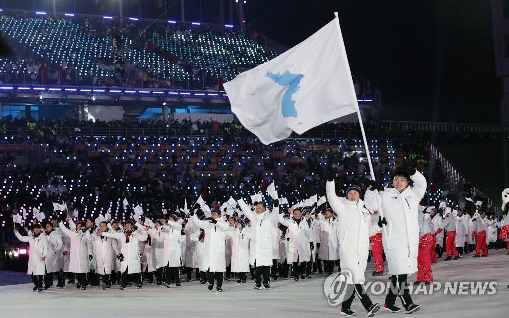 This file photo shows South and North Korean athletes marching together at the opening ceremony of the 2018 PyeongChang Winter Olympic Games in PyeongChang, 182 kilometers east of Seoul, on Feb. 9, 2018, while carrying a flag symbolizing a unified Korean Peninsula. The North's sports ministry said on its homepage on April 6, 2021, that the North will not participate in the Tokyo Olympic Games set for July 23-Aug. 8 due to concerns over the coronavirus pandemic. (Yonhap)