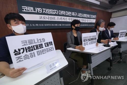 Activists hold signs at a press conference in Seoul, demanding the government come up with more support measures for small business owners and the self-employed hit hard by the pandemic on Sept. 16, 2021. (Yonhap)