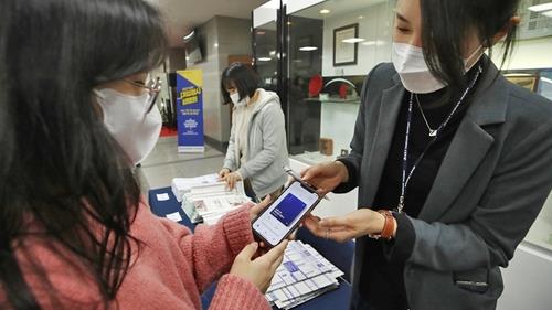 In this file photo, a mother of a student presents her vaccine pass before being allowed into a session regarding college entrance, held at a ward office in Seoul on Dec. 17, 2021. (Yonhap)