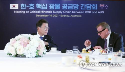 South Korean President Moon Jae-in (L) talks with Simon Crean, the Australian head of the Korea-Australia Economic Cooperation Committee, during a meeting at a Sydney hotel on Dec. 14, 2021, to discuss with Australian businesspeople ways to secure stable supply chains of raw materials and critical minerals between the two countries. (Yonhap)