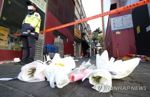 Bouquets of flowers lie on Oct. 31, 2022, in front of a police line that surrounds the site of the Oct. 29 crowd crush in Seoul's Itaewon district. (Yonhap)