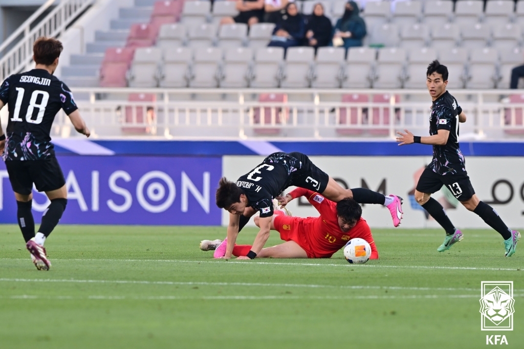 In this photo provided by the Korea Football Association, Kim Min-woo of South Korea (on top) gets tangled up with Jia Feifan of China during the teams' Group B match at the Asian Football Confederation U-23 Asian Cup at Abdullah bin Khalifa Stadium in Doha on April 19, 2024. (PHOTO NOT FOR SALE) (Yonhap)