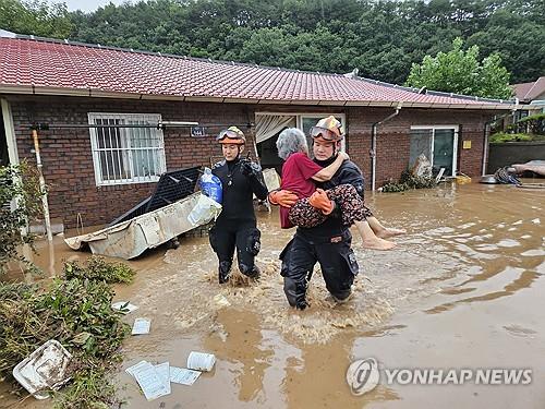 Esta fotografía, proporcionada por las autoridades de bomberos, muestra a los rescatistas evacuando a un aldeano en Wanju el 10 de julio de 2024. (FOTO NO A LA VENTA) (Yonhap) 