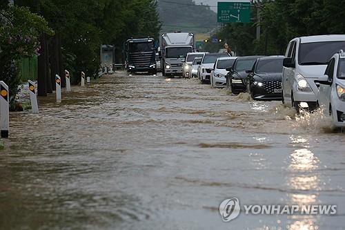 Los vehículos se desplazan lentamente por una carretera inundada en Paju, provincia de Gyeonggi, el 17 de julio de 2024, tras unas fuertes lluvias. (Yonhap)