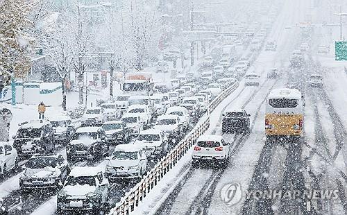 Los coches circulan lentamente por una carretera cubierta de nieve en Suwon, a unos 30 kilómetros al sur de Seúl, el 27 de noviembre de 2024, en medio de una alerta de fuertes nevadas. (Yonhap) 