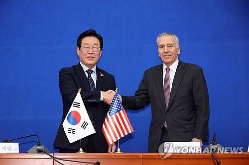 El representante Lee Jae-myung (izq.), líder del principal partido opositor, el Partido Demócrata, estrecha la mano del embajador de Estados Unidos en Corea del Sur, Philip Goldberg, durante su reunión en la Asamblea Nacional en Seúl, el 23 de diciembre de 2024. (Yonhap)