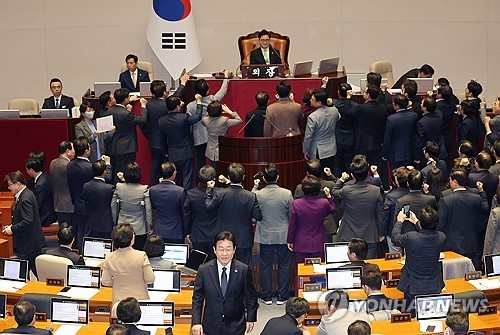 Ruling People Power Party lawmakers protest National Assembly Speaker Woo Won-shik's decision to set the quorum for acting President Han Duck-soo's impeachment at 151 votes, as main opposition Democratic Party leader Lee Jae-myung (C) walks to his seat, in the main hall of the National Assembly in Seoul on Dec. 27, 2024. (Yonhap)