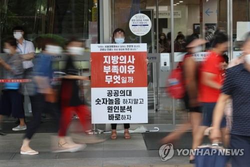 Un médecin brandit une pancarte critiquant le gouvernement dans un hôpital à Séoul le 27 août 2020, deuxième jour d'une grève de trois jours menée par des dizaines de milliers de médecins dans tout le pays pour protester contre la réforme du personnel médical du gouvernement. 