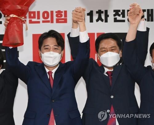 Lee Jun-seok (à g.), âgé 36 ans, est devenu le chef du principal parti de l'opposition, Parti du pouvoir du peuple (PPP), à l'issue des votes à la première convention du PPP, le vendredi 11 juin 2021, à Yeouido à Séoul. Lee et le chef du groupe parlementaire du PPP, Kim Gi-hyeon (à dr.), manifestent leur joie après l'annonce du résultat des votes.