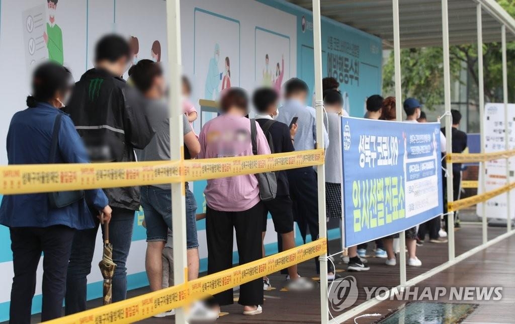 Des personnes font la queue avant de se soumettre à un test de dépistage du nouveau coronavirus (Covid-19) devant un centre provisoire de l'arrondissement de Seongbuk à Séoul, le mardi 15 juin 2021.