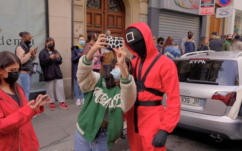 Une participant à l'évènement «Squid Game» tenu les 2 et 3 octobre 2021 à Paris en France prend un selfie avec un assistant portant le costume de la série télévisée. 