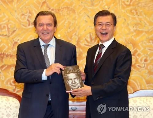 シュレーダー氏（左）から自伝を贈られ笑顔を見せる文大統領＝１２日、ソウル（聯合ニュース）