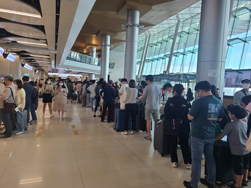 金浦空港の国内線ターミナルでチェックインの列に並ぶ人々＝（聯合ニュース）