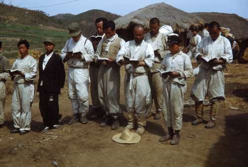 1951년 피란길 도중 마을 집 앞에서 성경책 읽는 사람들