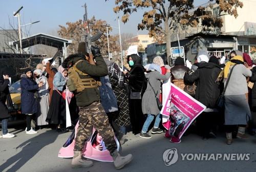 28일 아프간 카불에서 시위하는 여성과 근처의 탈레반.