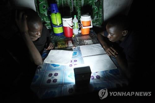아프리카 라이베리아의 한 가정에서 학생들이 손전등으로 공부하는 모습