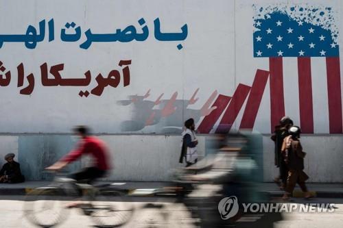 탈레반이 카불에서 미국 국기를 조롱하는 내용의 벽화 앞을 지나는 모습