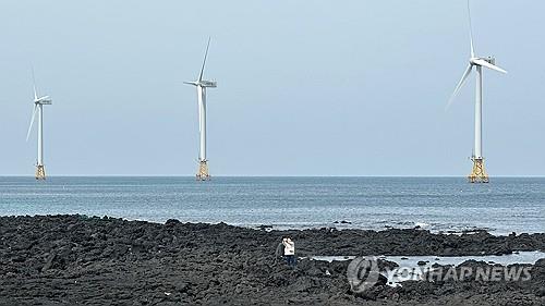 제주 한경면 해안의 풍력발전기를 배경으로 사진 찍는 관광객들