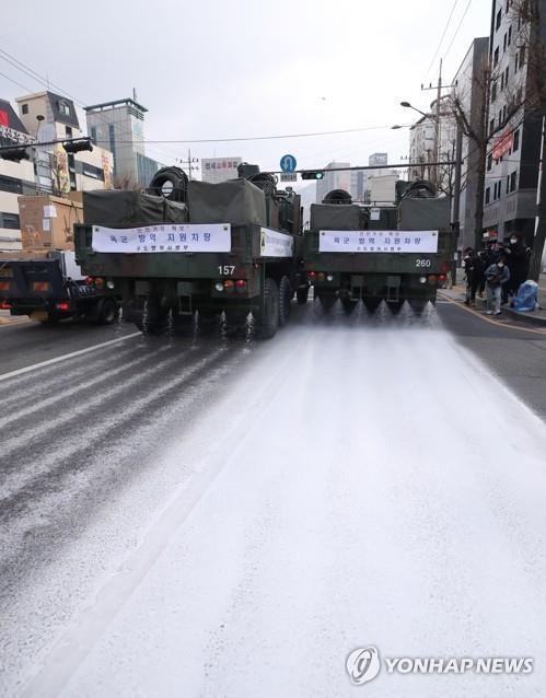 Unos vehículos militares del Comando de Defensa de la Capital realizan trabajos de desinfección, el 4 de marzo de 2020, en una calzada de Seúl, como parte de las medidas preventivas contra la propagación del COVID-19.