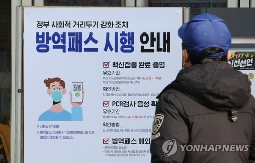 Una persona lee un letrero sobre el sistema del pase de vacunación contra el COVID-19, pegado en la puerta de un hipermercado, el 10 de enero de 2022, en Seúl.