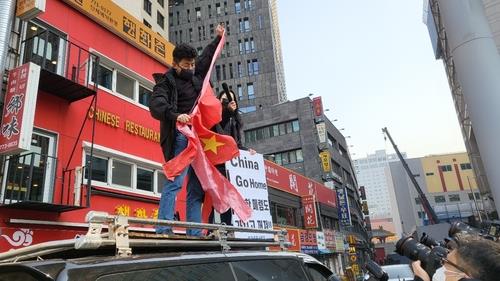 Unos manifestantes destrozan la bandera china durante una protesta en Seúl por el arbitraje olímpico