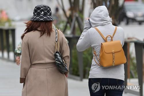 Las personas, que visten ropa ligera de invierno, caminan por el centro de Seúl, el 10 de octubre de 2022, mientras la temperatura mínima matinal cayó drásticamente.